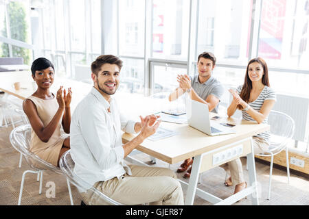 Multiethnic group of happy young business people clapping hands on presentation in office Stock Photo