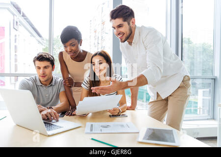 Group of happy young business people using laptop and working together in office Stock Photo