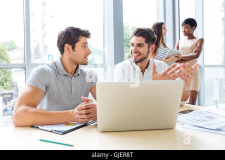 Happy young businessmen and businesswomen working in office Stock Photo