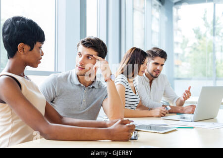 Group of young business people sitting and talking in office Stock Photo