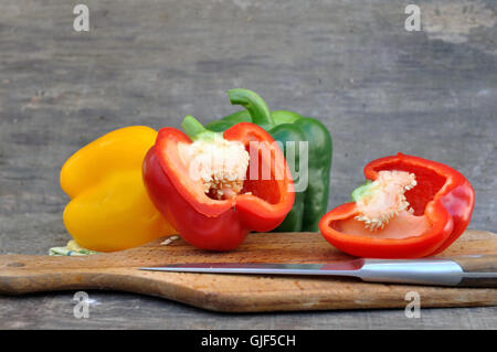 red pepper cut in half with others on board with knife Stock Photo