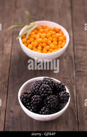 Blackberries and sea buckthorn on wooden table Stock Photo