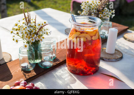 Fresh compote, fruits, candles and flowers on wooden table closeup. Selective focus. Beutiful decoration in boho style. Stock Photo