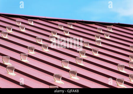 Clear plastic snow guards or snow stops on a sloping wooden roof Stock Photo