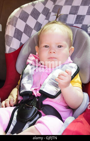 little newborn baby girl rests in the car seat Stock Photo