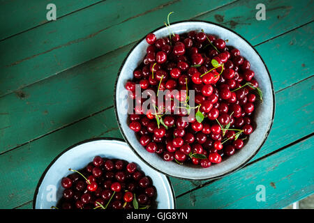 Bowl filled with Organic cherries on green table background Stock Photo