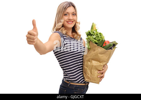 Smiling woman giving a thumb up and holding a bag of groceries isolated on white background Stock Photo