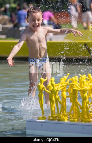 Edinburgh, Scotland, UK. 16th August, 2016. UK Weather: Four year old Samuel Surlit from Edinburgh plays in the ponds in-front of the Scottish Parliament where the Edinburgh International Festival art installation, Anything That Gives Off Light is on display. Credit:  Richard Dyson/Alamy Live News Stock Photo