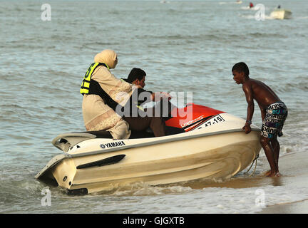 Penang, MALAYSIA. 24th Feb, 2016. A Muslim woman wearing a full burqa rides a WaverRunner with a man during a day at the beach in Penang, Malaysia on February 21, 2016. The mayor of Cannes in southern France has banned full-body swimsuits known as ''burkinis'' from the beach, citing public security concerns and fears. © Stephen Shaver/ZUMA Wire/Alamy Live News Stock Photo