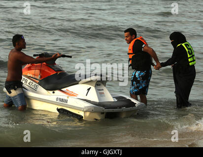 Penang, MALAYSIA. 24th Feb, 2016. A Muslim woman wearing a full burqa rides a WaverRunner with a man during a day at the beach in Penang, Malaysia on February 21, 2016. The mayor of Cannes in southern France has banned full-body swimsuits known as ''burkinis'' from the beach, citing public security concerns and fears. © Stephen Shaver/ZUMA Wire/Alamy Live News Stock Photo