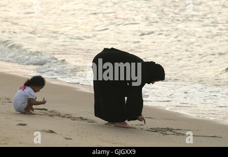 Penang, MALAYSIA. 24th Feb, 2016. A Muslim woman, wearing a full burqa, writes in the sand during a day at the beach in Penang, Malaysia on February 21, 2016. The mayor of Cannes in southern France has banned full-body swimsuits known as ''burkinis'' from the beach, citing public security concerns and fears. © Stephen Shaver/ZUMA Wire/Alamy Live News Stock Photo