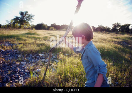 Boy holding wooden walking stick on walk Stock Photo
