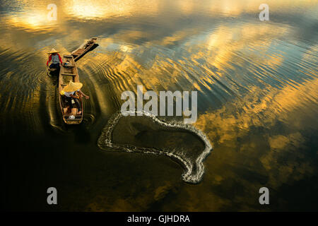 Two fishermen casting a net in river at sunrise, Thailand Stock Photo