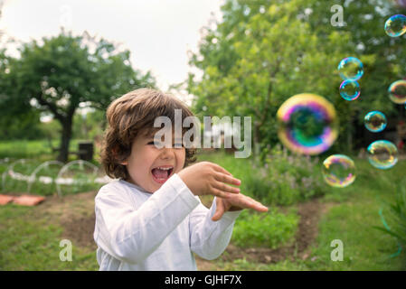 Laughing boy playing with soap bubbles Stock Photo
