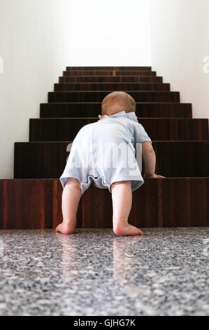 Baby boy climbing wooden stairs Stock Photo