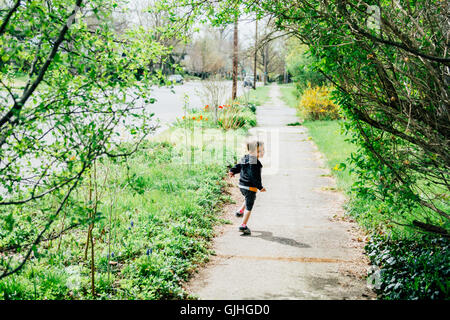 Boy running along pavement looking over his shoulder Stock Photo