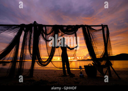 Silhouette of a man standing on beach by fishing nets, Penang, Malaysia Stock Photo