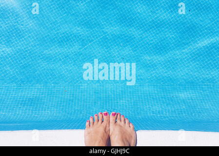 Close-up of a woman's feet at the edge of a swimming pool Stock Photo