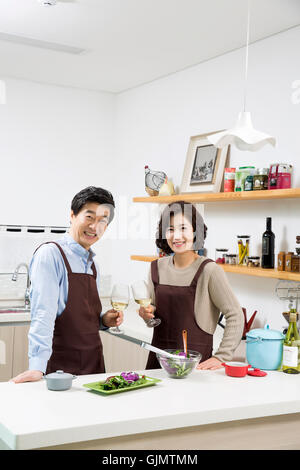 Middleaged Asian Couple Having White Wine in Kitchen Stock Photo