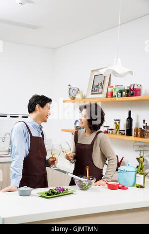 Middleaged Asian Couple Having White Wine in Kitchen Stock Photo