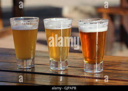 A selection of three craft beers during a tasting session on a wooden table Stock Photo