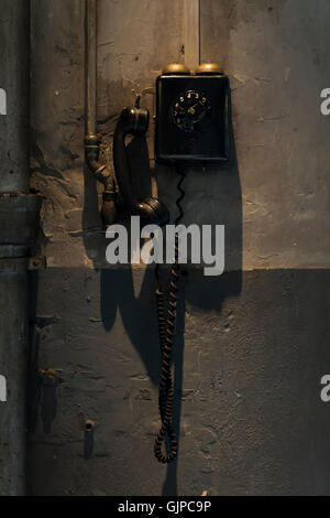 An old black telephone hanging on the wall inside a workshop Stock Photo
