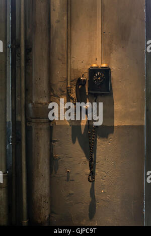 An old black telephone hanging on the wall inside a workshop Stock Photo