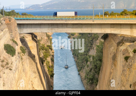 Large truck traversing the bridge of isthmus of Corinth in Greece while the boats are travelling in the bottom. Stock Photo
