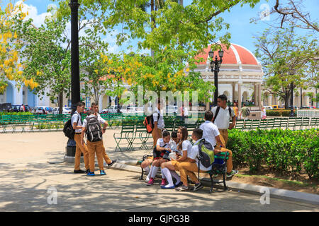 Group of school children chat and wait in Parque Marti, Cienfuegos, Cuba Stock Photo