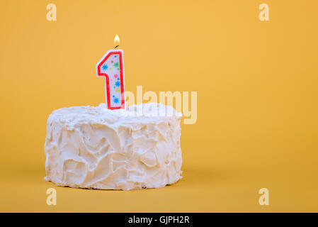 White frosted cake with candle 1 lit on top of it. Stock Photo