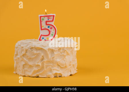 Frosted cake with number five candle Stock Photo