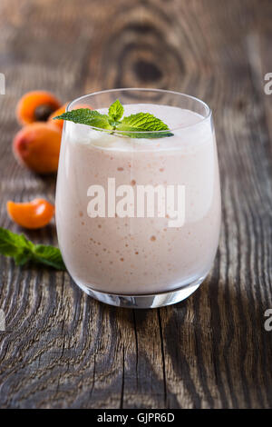 Homemade fresh summer fruits milkshake with toasted marshmallow and ripe apricots on rustic wooden background Stock Photo