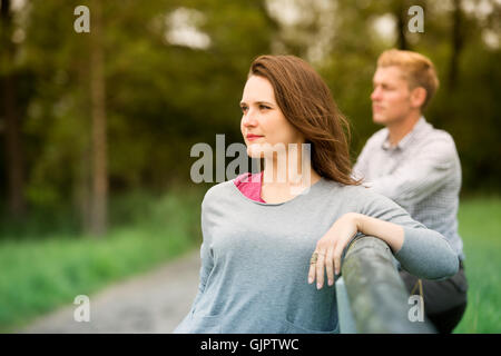 woman and man leaning against a fence on farmland Stock Photo