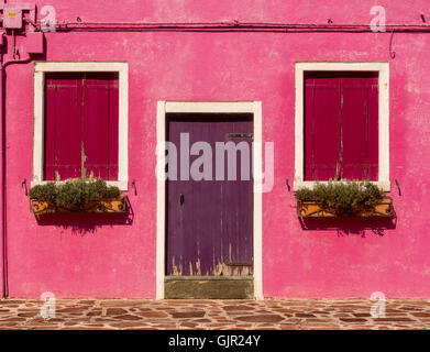 Pink rendered exterior of a traditional house, with purple door on the island of Burano. Venice, Italy. Stock Photo