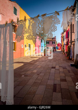 Washing line with laundry pegged on it drying in the backyards of traditional colourful painted terrace houses of the island of Burano. Venice, Italy. Stock Photo