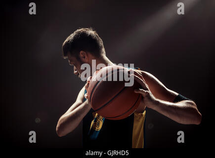 Silhouette view of a basketball player holding basket ball on black background Stock Photo