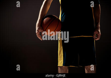 Silhouette view of a basketball player holding basket ball on black background Stock Photo