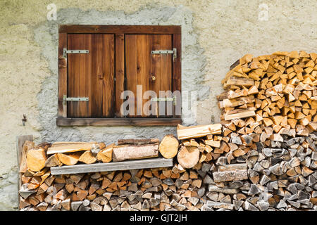 A closed farmhouse window with timber piled underneath Stock Photo