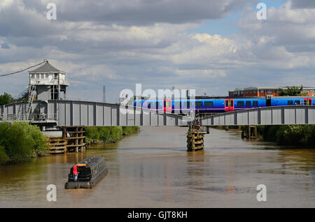 trans pennine express train crossing selby swing bridge spanning the river ouse with narrow boat passing underneath ,selby, uk Stock Photo