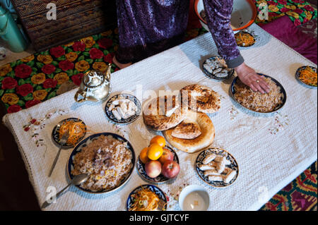 Kyrgyzstan, Jalabat: A typical Central Asian dinner, rice with some meat, green tea, salad, fruits and some sweets. Stock Photo