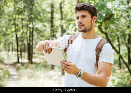 Serious young man with backpack using tablet outdors Stock Photo