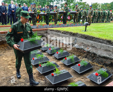 Lebus, Germany. 18th Aug, 2016. A Russian soldier places small coffins containing the remains of Soviet soldiers from the second world war into a grave, during their burial at the military cemetary in Lebus, Germany, 18 August 2016. The 35 red army soldiers died in the heavy fighting in the Oderbruch area in early 1945. The mortal remains were recovered by the German War Graves Commission last year, and can now finally be laid to rest, more than 70 years after the war's end. PHOTO: PATRICK PLEUL/DPA/Alamy Live News Stock Photo
