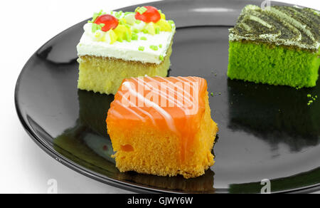Mini cakes orange and cake green tea ,cakes cream on a black plate Stock Photo