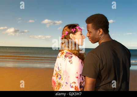 Attractive couple multicultural mixed race head and shoulders  looking into each others eyes in love on beach  romantic emotions Stock Photo