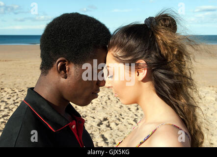 Young couple multicultural mixed race head shot on beach  eyes closed heads touching romantic emotions love Stock Photo