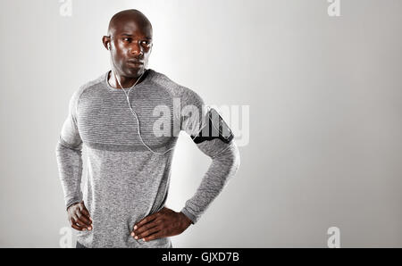 Shot of handsome young african man in long sleeve shirt listening to music and looking away. Fit male model standing with his ha Stock Photo