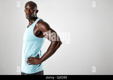 Portrait of confident young african man with muscular build standing against grey background. Afro american fitness male model w Stock Photo