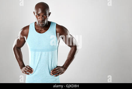 Portrait of healthy young african man standing against grey background with copy space. fitness male model standing with his han Stock Photo