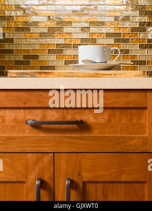 High quality wood cabinets with bronze cabinet hardware & glass tile mosaic backsplash in contemporary upscale home kitchen interior Stock Photo