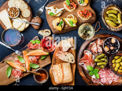Italian antipasti wine snacks set. Brushettas, cheese variety, Mediterranean olives, pickles, Prosciutto di Parma with melon, sa Stock Photo